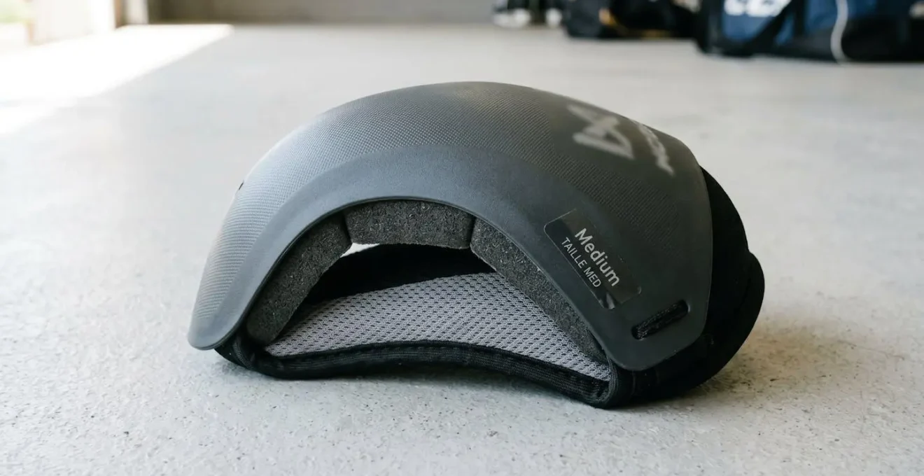 Une coquille de protection pour sports de combat posée sur surface neutre avec étiquette de taille visible